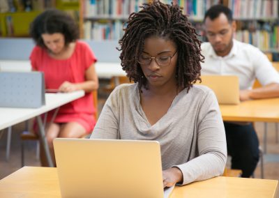 Front view of concentrated woman working with laptop at library
